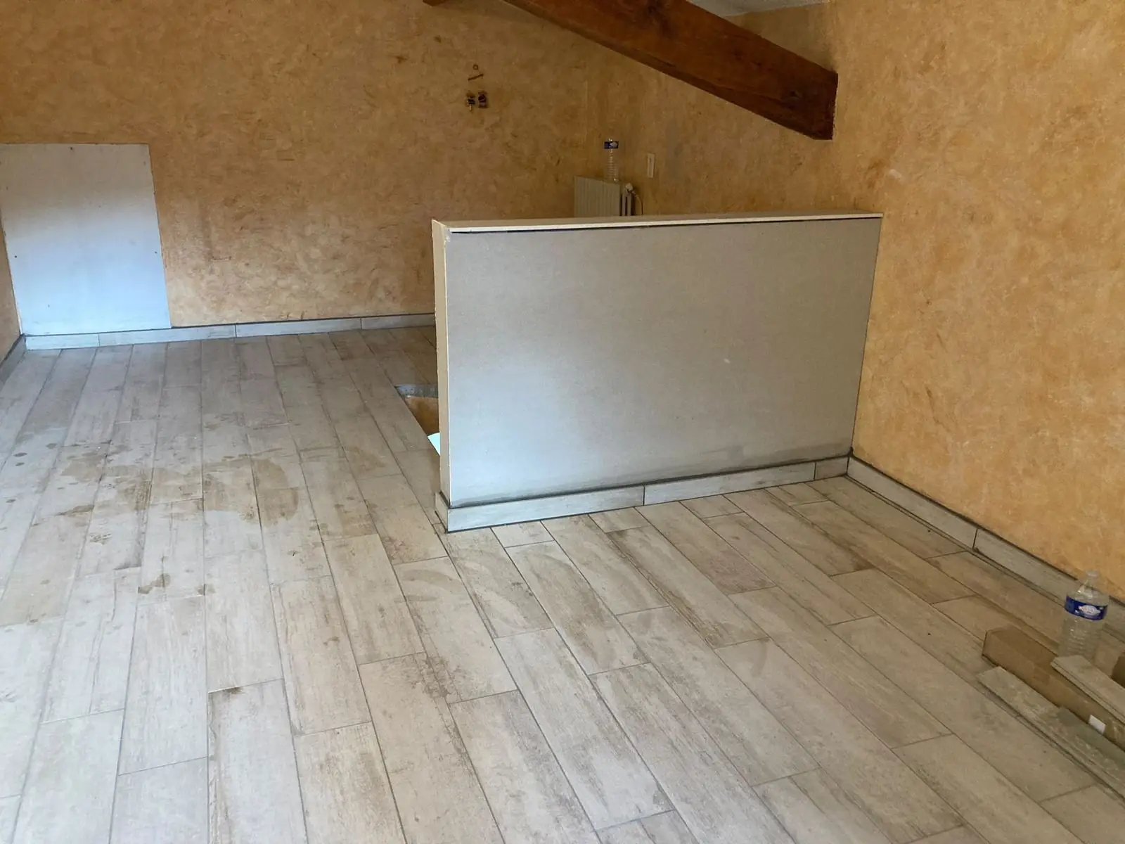 Pièce entièrement rénovée par André Bâtiment : carrelage effet parquet et muret
